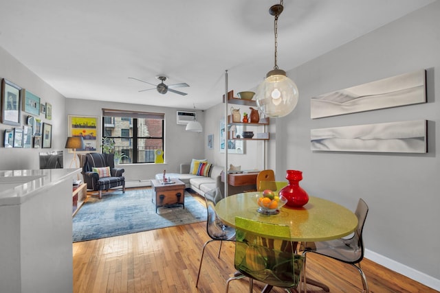 dining room with ceiling fan, a wall mounted air conditioner, baseboards, and wood finished floors