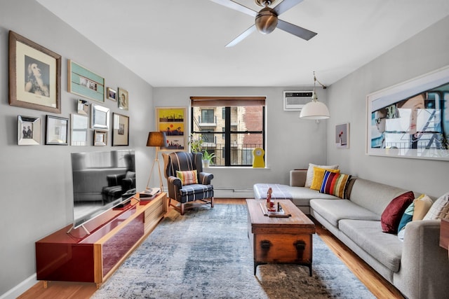 living area with baseboards, wood finished floors, baseboard heating, a ceiling fan, and an AC wall unit
