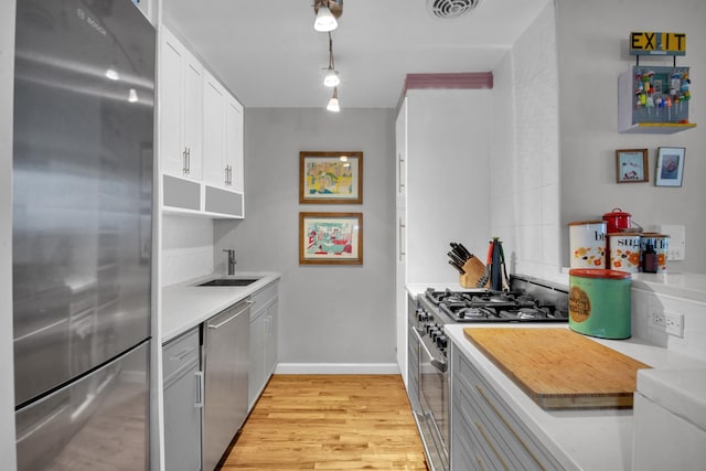 kitchen featuring light countertops, stainless steel appliances, a sink, light wood-style floors, and visible vents