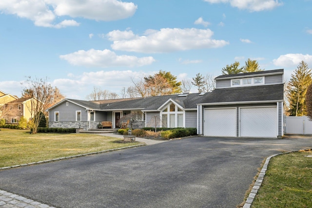 view of front of home featuring a gate, fence, driveway, a front lawn, and stone siding