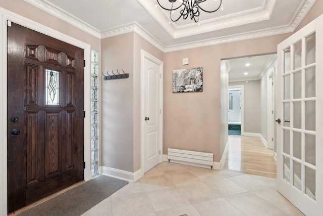 entryway with crown molding, light tile patterned flooring, a tray ceiling, and a chandelier