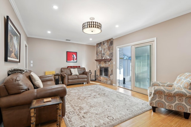 living area featuring visible vents, ornamental molding, a stone fireplace, recessed lighting, and wood finished floors