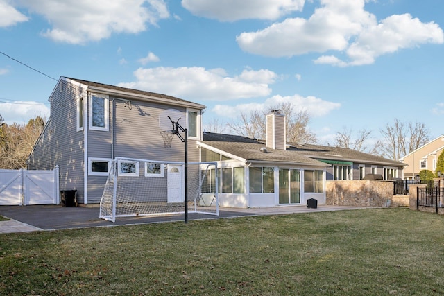 rear view of property with a gate, fence, a sunroom, a chimney, and a lawn