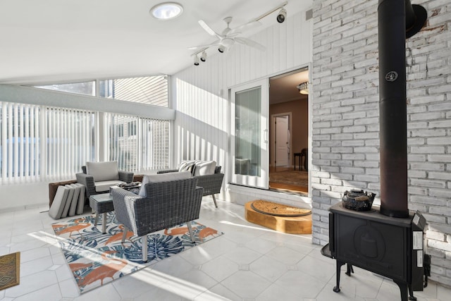 living area with light tile patterned floors, ceiling fan, and a wood stove