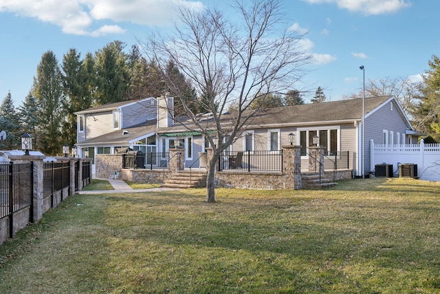 rear view of house featuring a lawn, central AC unit, a chimney, and fence