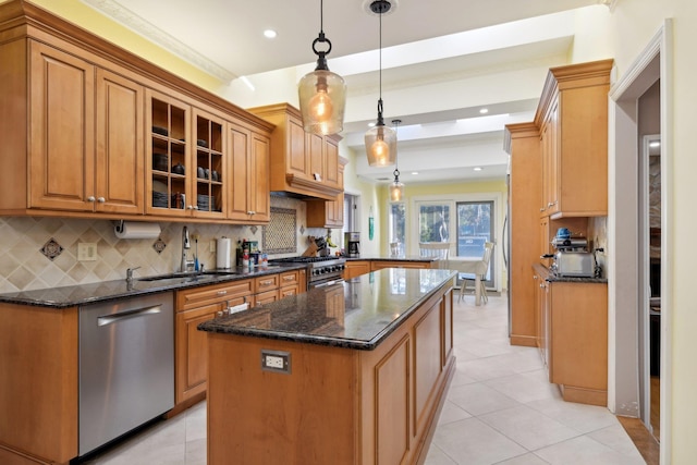 kitchen featuring a sink, glass insert cabinets, appliances with stainless steel finishes, tasteful backsplash, and a center island