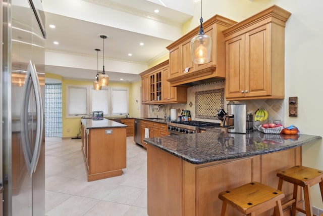 kitchen with a kitchen island, decorative backsplash, appliances with stainless steel finishes, a peninsula, and a sink