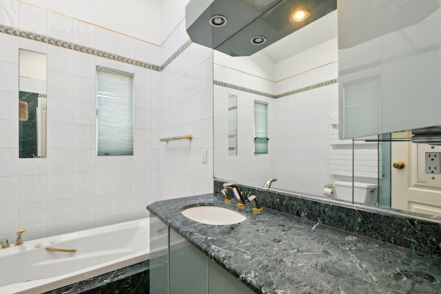 full bath with tile walls, vanity, and a garden tub