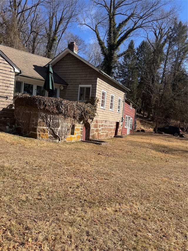 view of side of property with a yard and a chimney