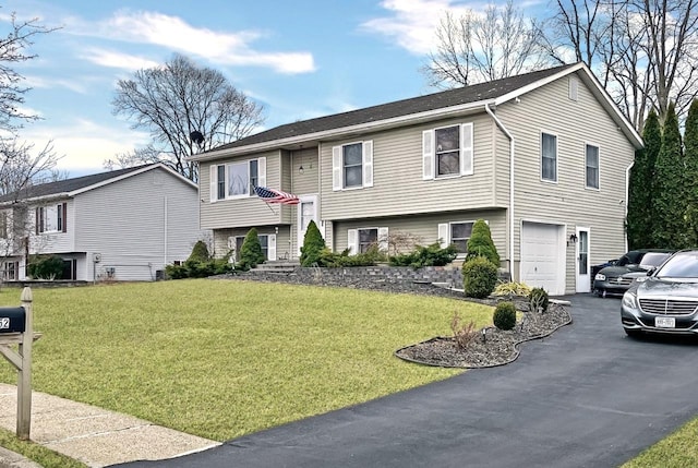 raised ranch with a garage, a front yard, and driveway