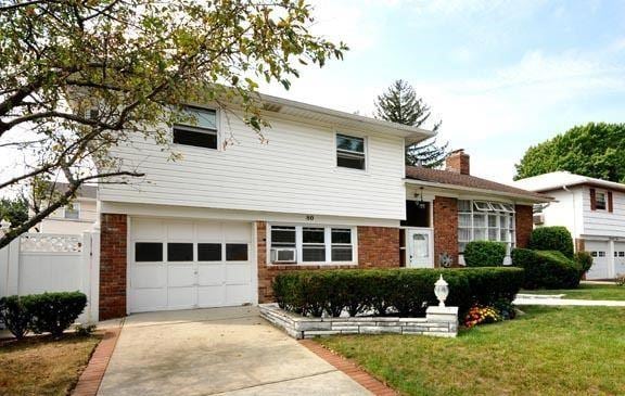 tri-level home featuring a garage, driveway, and brick siding