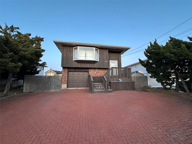 view of front facade with decorative driveway, brick siding, and fence