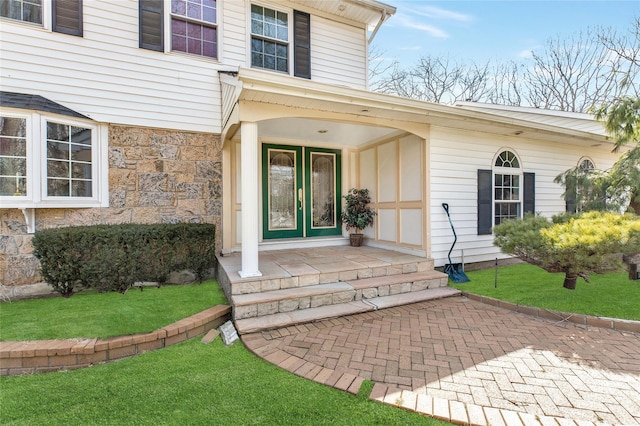 doorway to property with stone siding and a lawn