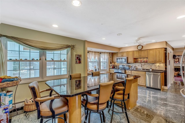 kitchen featuring dark countertops, appliances with stainless steel finishes, a kitchen breakfast bar, and a center island