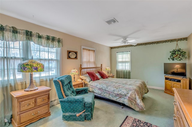 bedroom featuring a baseboard heating unit, light carpet, a ceiling fan, visible vents, and baseboards