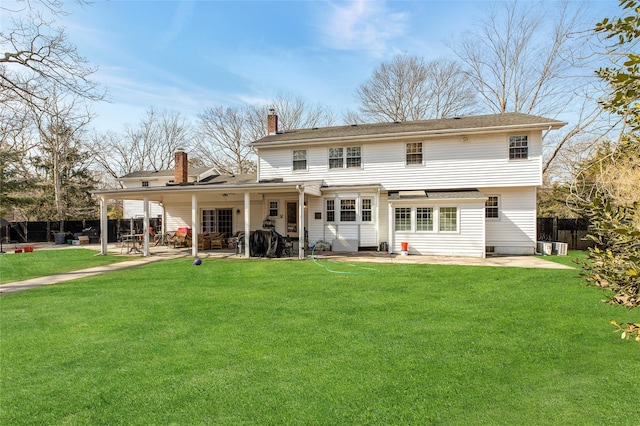 back of property with fence, a patio, a chimney, and a lawn