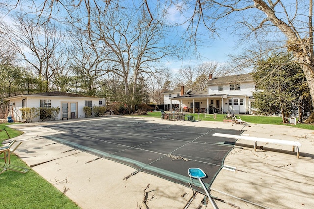 view of pool with french doors, a patio area, a covered pool, and a diving board