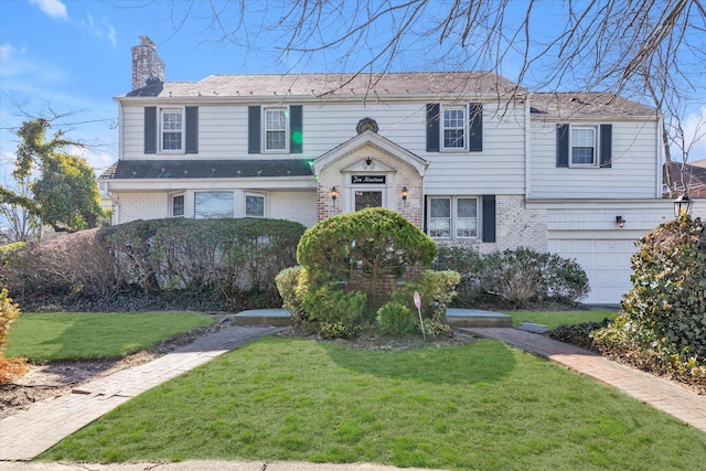 view of front of house featuring brick siding, a garage, a chimney, and a front lawn