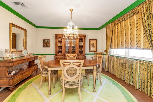 dining area with an inviting chandelier, wood finished floors, visible vents, and ornamental molding