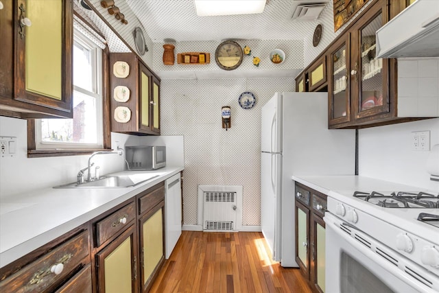 kitchen with extractor fan, dark wood finished floors, light countertops, white appliances, and a sink