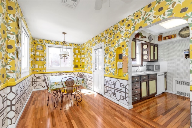 dining area featuring visible vents, hardwood / wood-style floors, radiator heating unit, and wallpapered walls