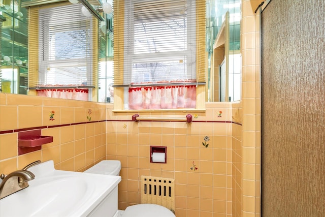 bathroom with an enclosed shower, toilet, tile walls, and a sink