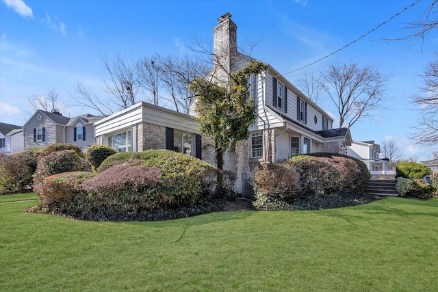 view of side of property with brick siding, a chimney, and a lawn