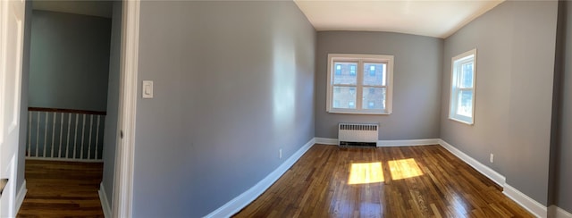 spare room featuring radiator heating unit, a healthy amount of sunlight, baseboards, and dark wood-style flooring