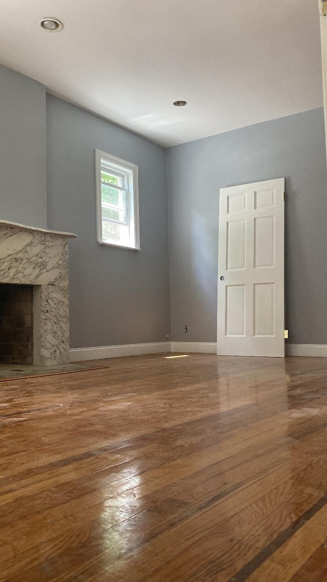 unfurnished living room with baseboards, wood finished floors, and a fireplace