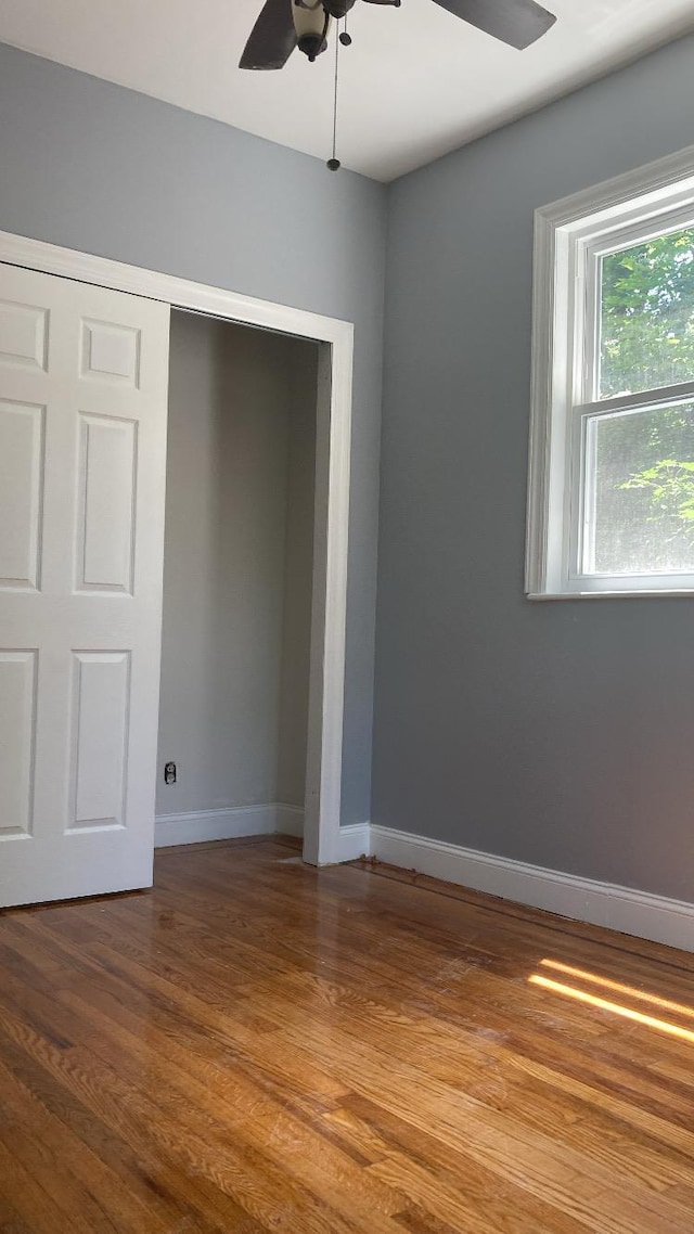 unfurnished bedroom with ceiling fan, a closet, baseboards, and wood finished floors