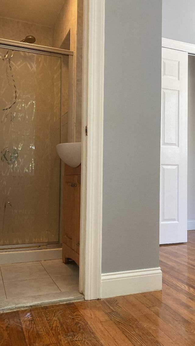 bathroom featuring wood finished floors, a stall shower, and baseboards