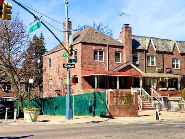 view of front of property with fence, brick siding, and a chimney