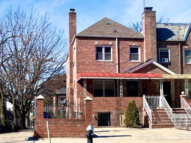 view of front of property featuring brick siding, a porch, and a chimney