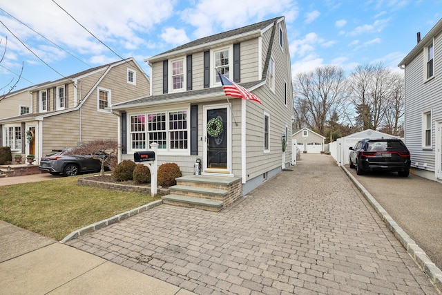 view of front of house featuring an outbuilding, a gambrel roof, and a front lawn