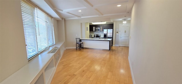 kitchen featuring beam ceiling, light wood-style flooring, coffered ceiling, stainless steel appliances, and baseboards