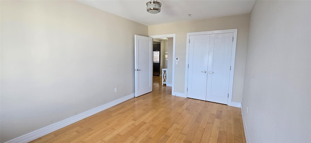 unfurnished bedroom with a closet, baseboards, and light wood finished floors