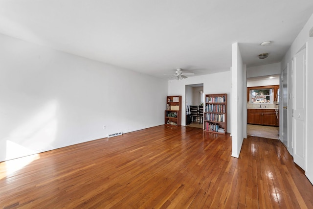 unfurnished living room with visible vents, a sink, a ceiling fan, and hardwood / wood-style floors