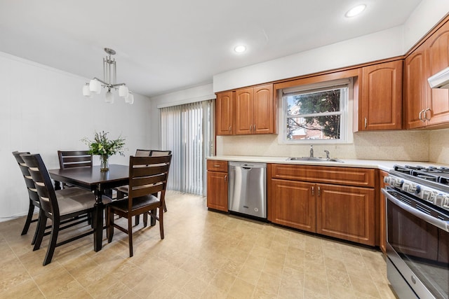 kitchen featuring an inviting chandelier, a sink, light countertops, appliances with stainless steel finishes, and brown cabinets