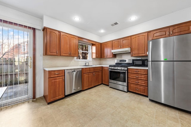 kitchen with visible vents, under cabinet range hood, a sink, appliances with stainless steel finishes, and light countertops