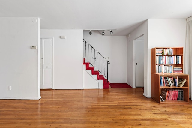 interior space with track lighting, stairway, and wood finished floors