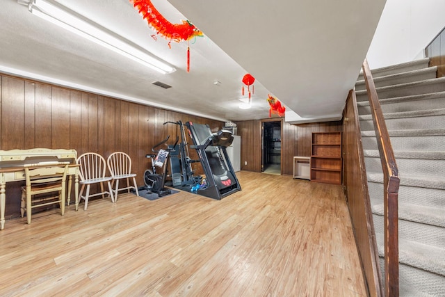 workout area featuring visible vents, wood walls, and wood finished floors