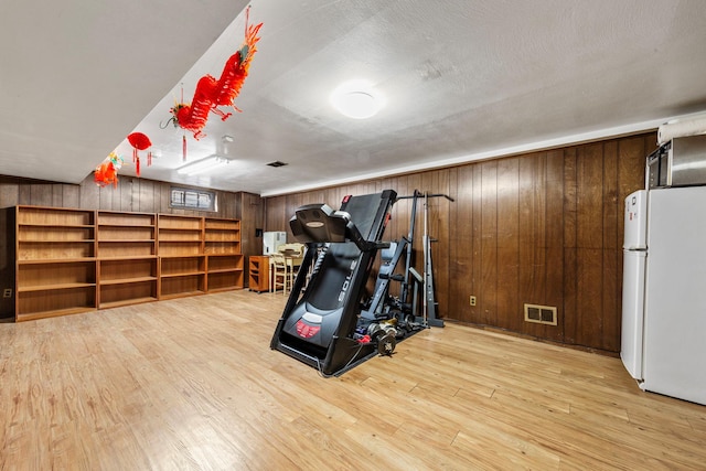 workout room with visible vents, wooden walls, and wood finished floors