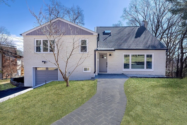 split level home featuring brick siding, a chimney, a front yard, and roof with shingles