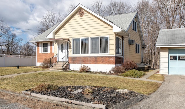 bungalow-style house with brick siding, a shingled roof, a front lawn, fence, and entry steps