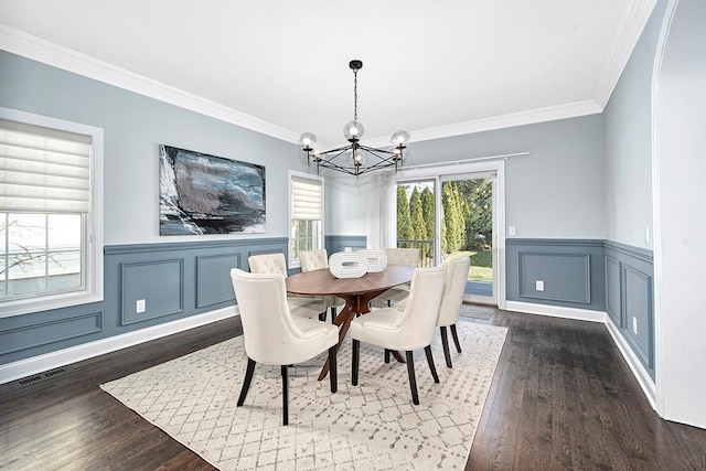 dining area featuring dark wood finished floors, crown molding, a notable chandelier, and visible vents