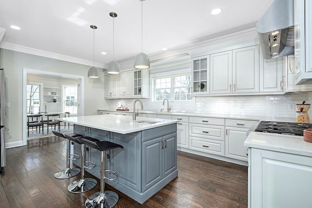 kitchen featuring dark wood finished floors, a sink, white cabinets, glass insert cabinets, and crown molding