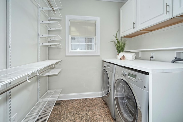 washroom with cabinet space, baseboards, and separate washer and dryer