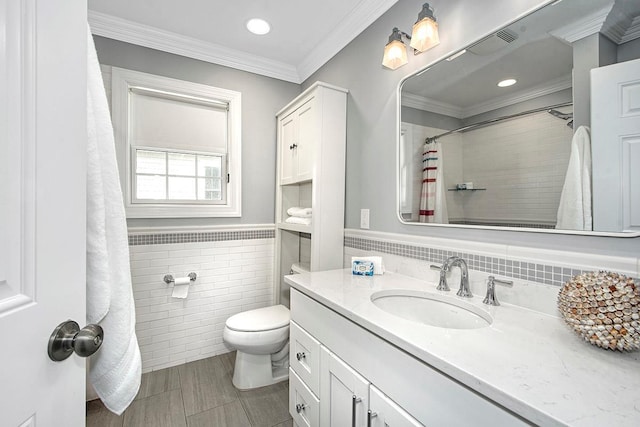 bathroom with toilet, ornamental molding, tile walls, wainscoting, and vanity