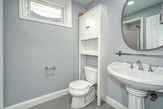 bathroom with tile patterned flooring, toilet, baseboards, and a sink