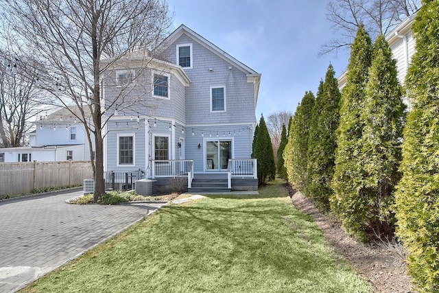 rear view of house featuring a lawn and fence